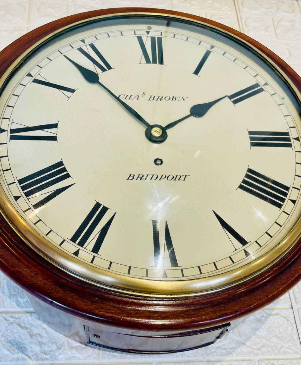 A circular Georgian fusee wall clock with a dark mahogany frame, a cream painted dial with Roman numerals, and a polished brass bezel. View VII