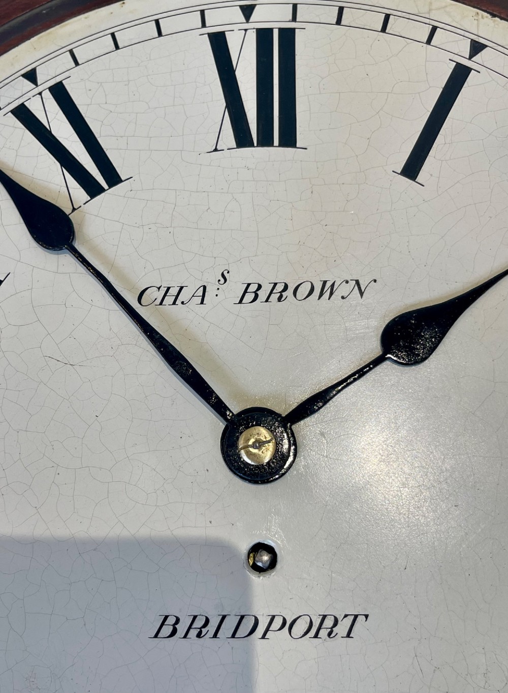 A circular Georgian fusee wall clock with a dark mahogany frame, a cream painted dial with Roman numerals, and a polished brass bezel. View VIII