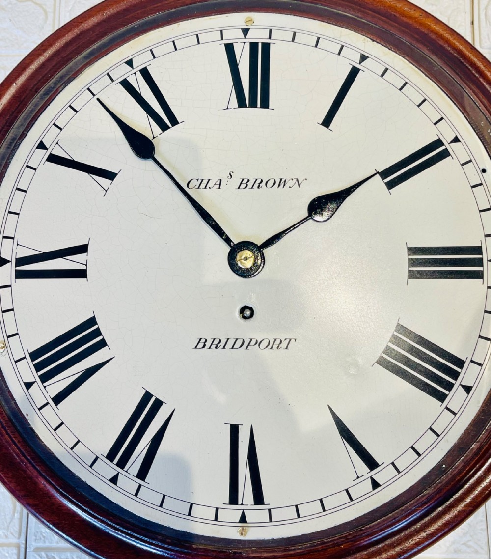 A circular Georgian fusee wall clock with a dark mahogany frame, a cream painted dial with Roman numerals, and a polished brass bezel. View X