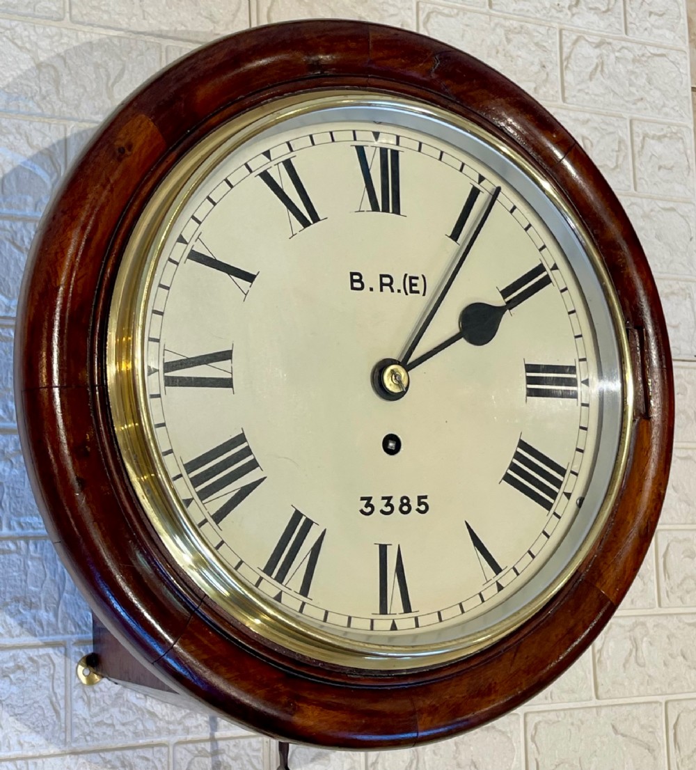 A circular antique mahogany railway dial wall clock with a painted off-white face, Roman numerals, brass bezel, and British Railways marking. View II
