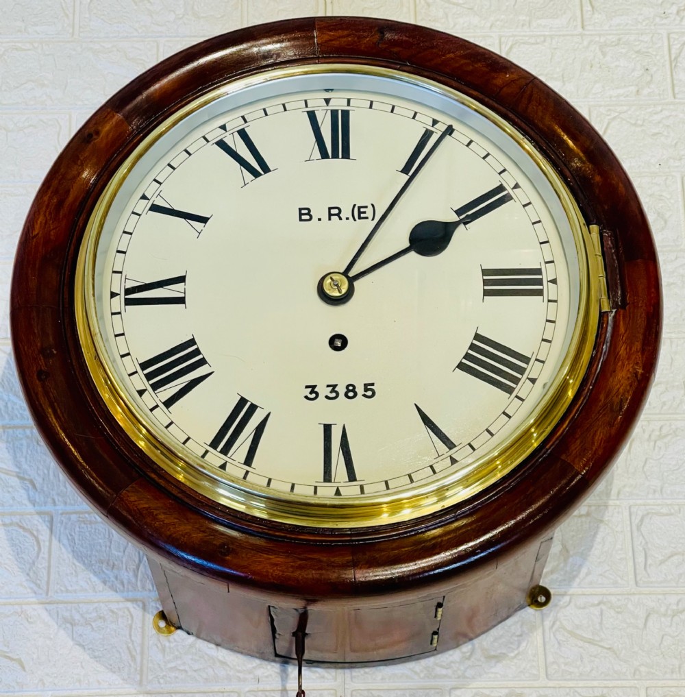 A circular antique mahogany railway dial wall clock with a painted off-white face, Roman numerals, brass bezel, and British Railways marking. View VII