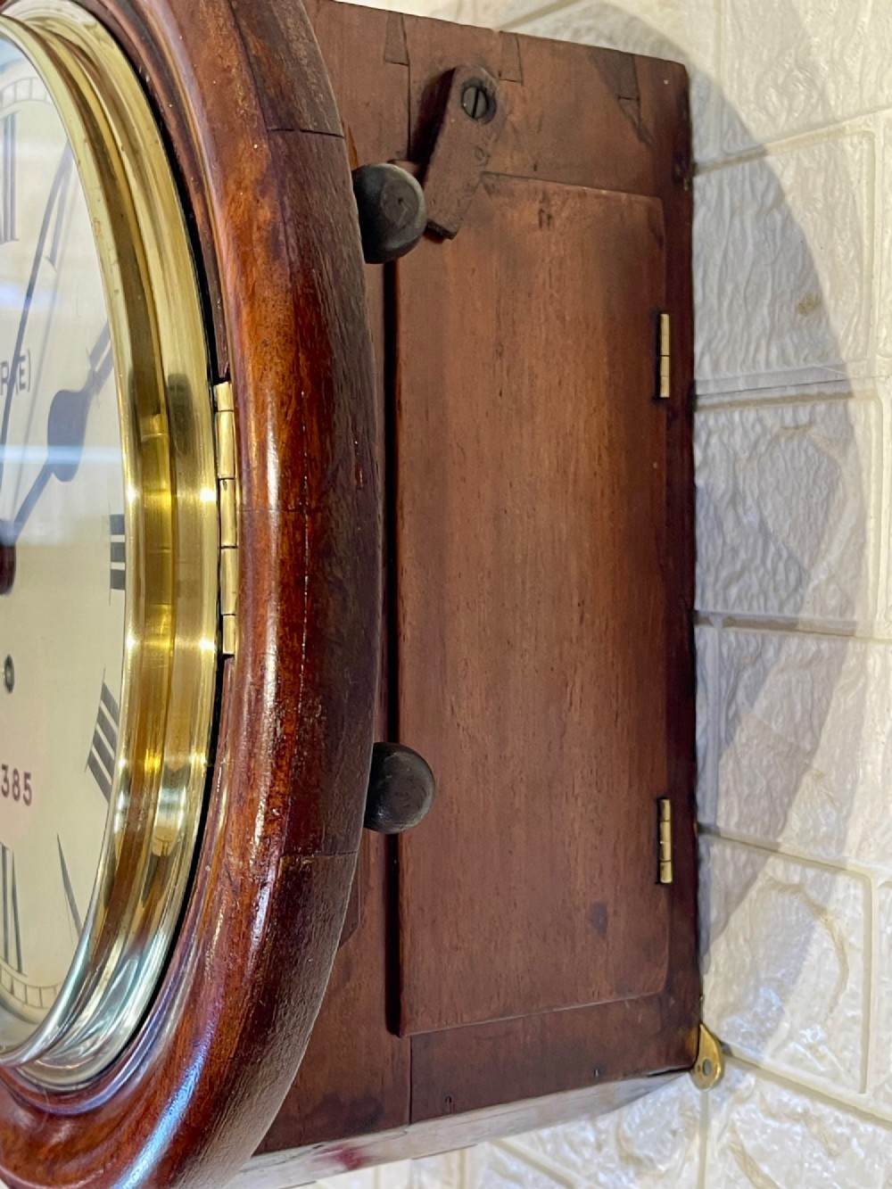 A circular antique mahogany railway dial wall clock with a painted off-white face, Roman numerals, brass bezel, and British Railways marking. View XII