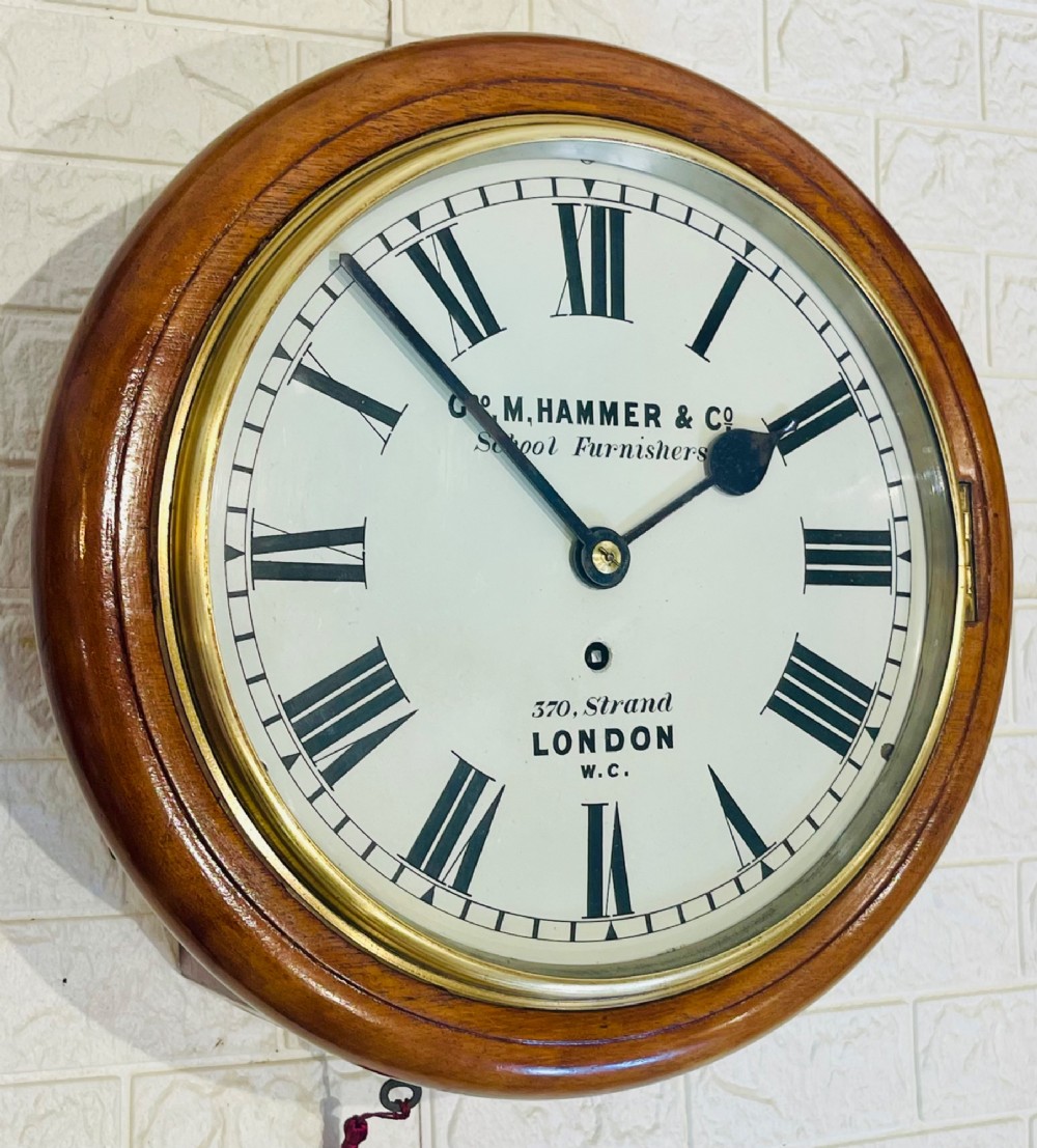 A circular Victorian mahogany wall clock featuring a white dial with black Roman numerals, a polished brass bezel, and London maker inscription. View II