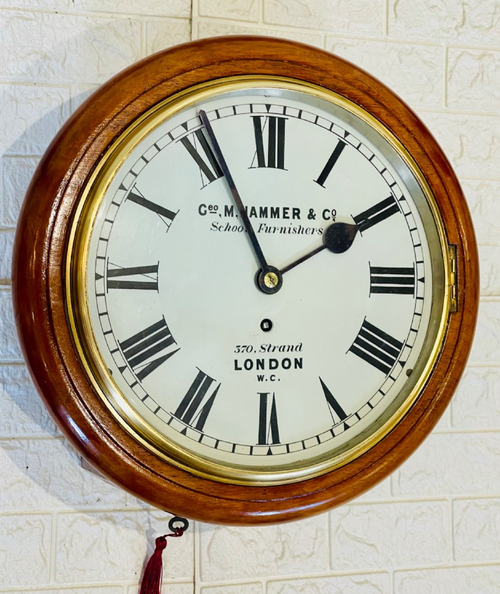 A circular Victorian mahogany wall clock featuring a white dial with black Roman numerals, a polished brass bezel, and London maker inscription. View XI