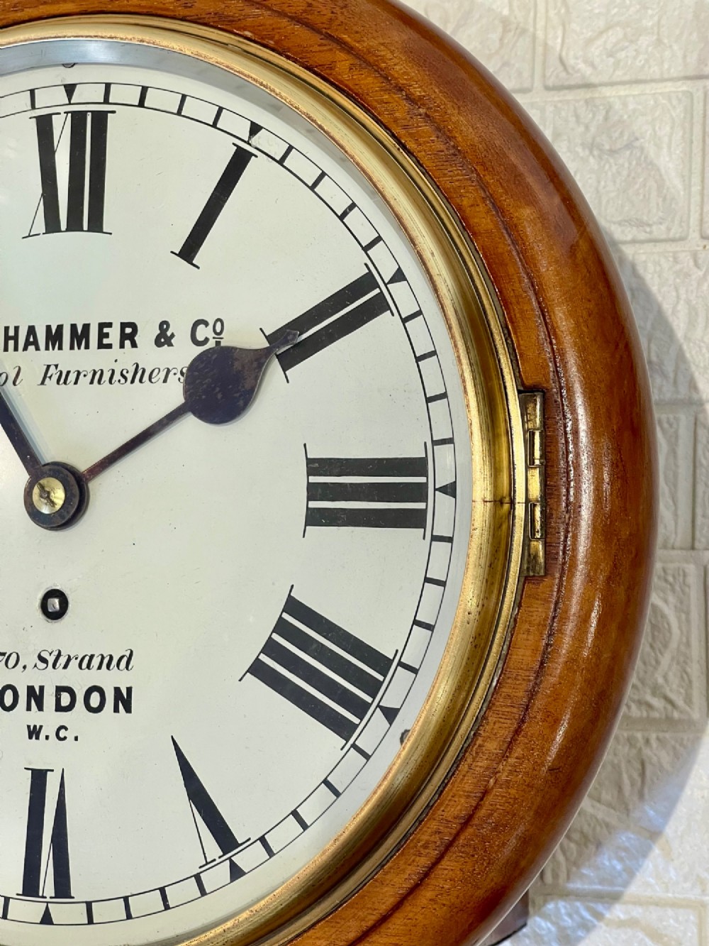 A circular Victorian mahogany wall clock featuring a white dial with black Roman numerals, a polished brass bezel, and London maker inscription. View XIII