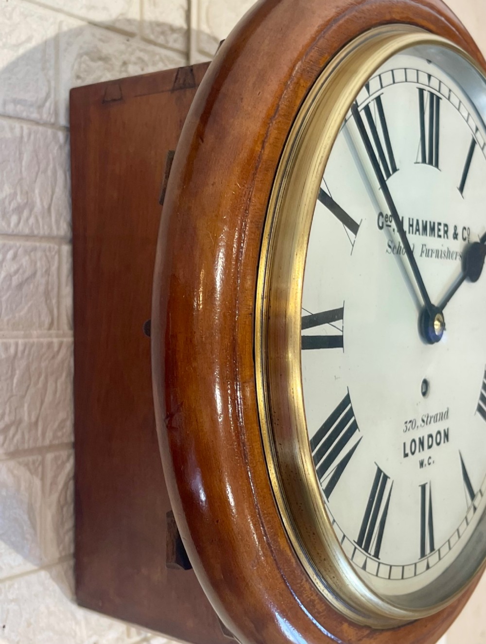 A circular Victorian mahogany wall clock featuring a white dial with black Roman numerals, a polished brass bezel, and London maker inscription. View XIV