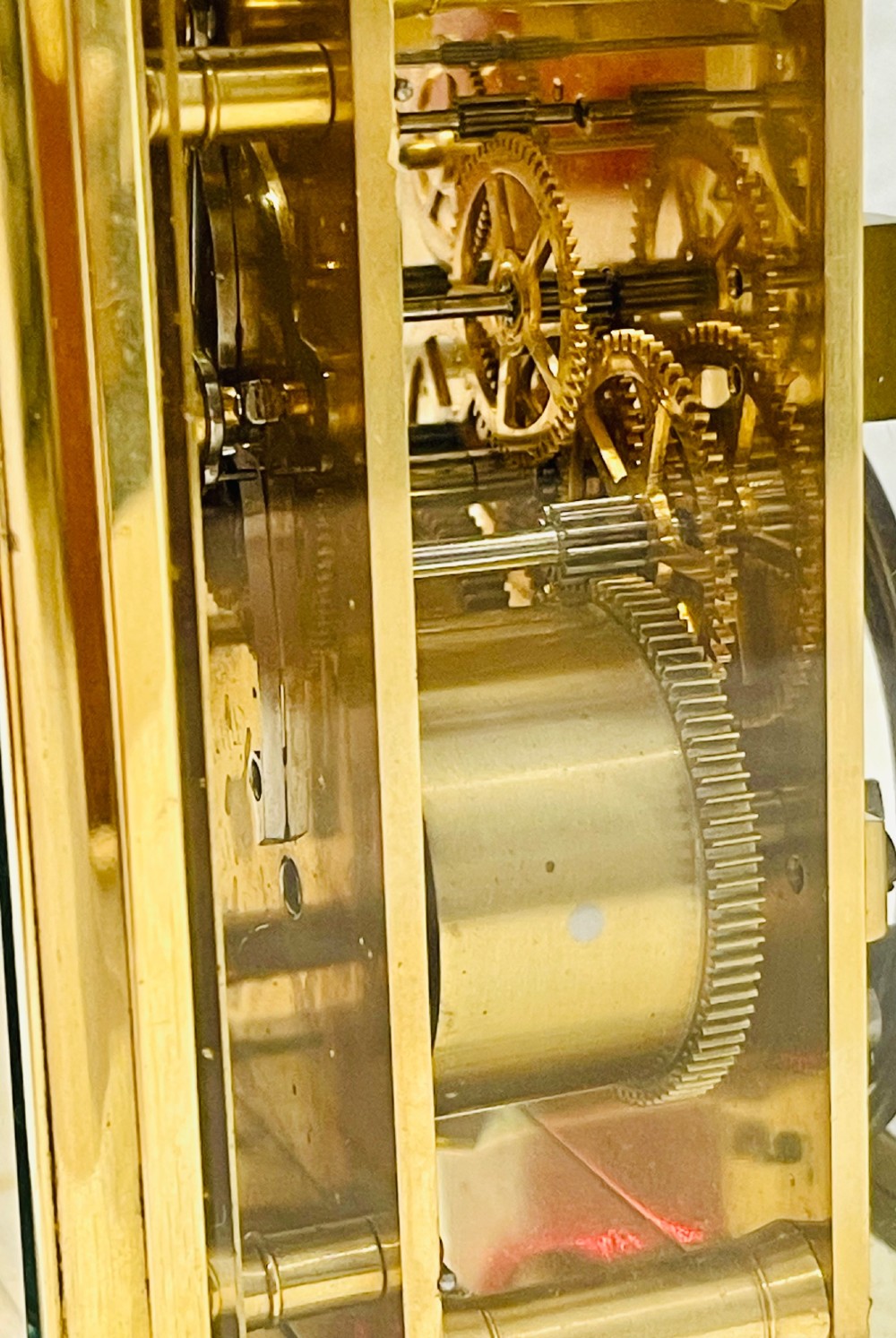 A French brass carriage clock featuring a top carrying handle, clear glass viewing panels, and a white enamel dial with black numerals. View VI