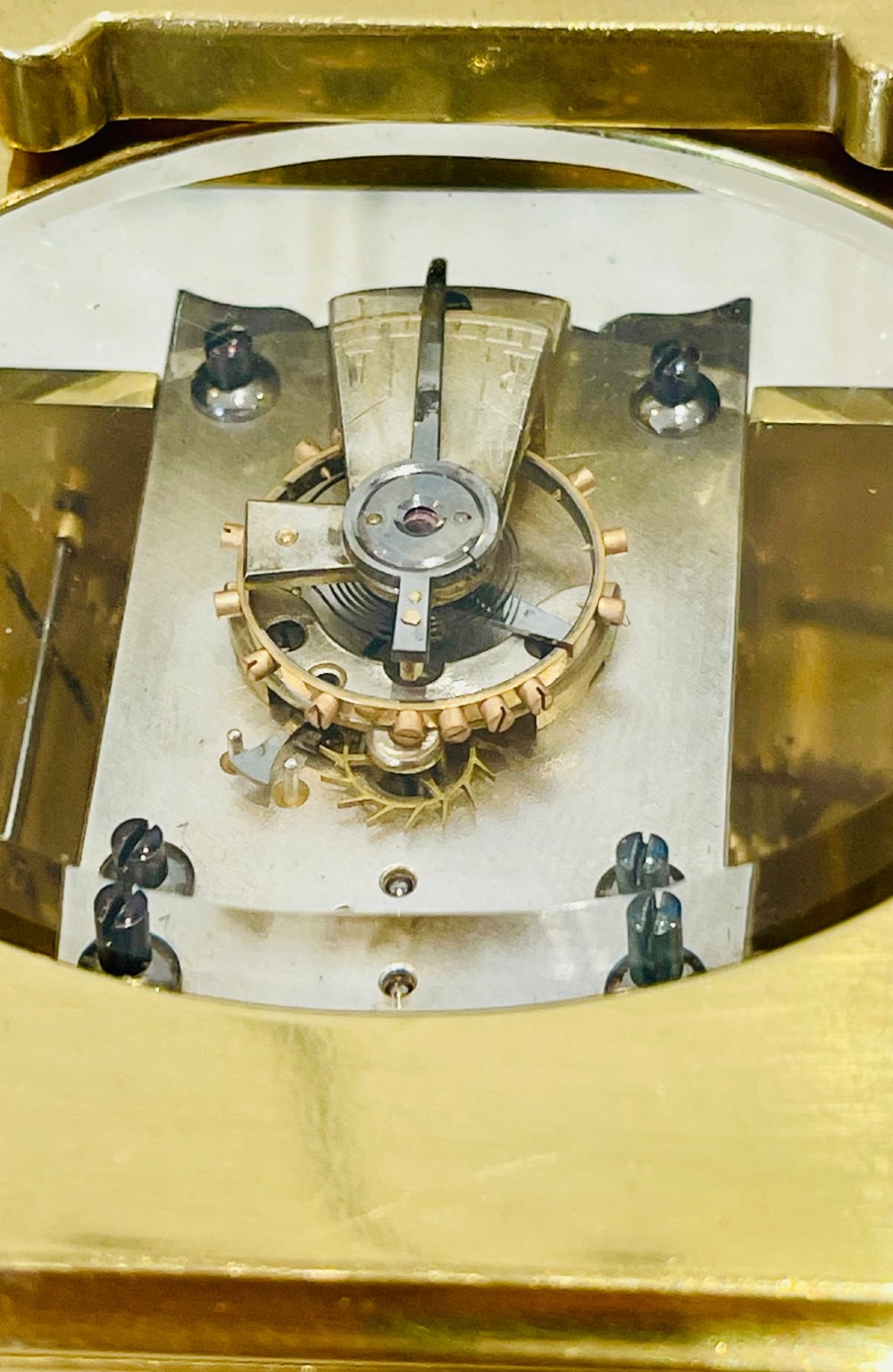 A French brass carriage clock featuring a top carrying handle, clear glass viewing panels, and a white enamel dial with black numerals. View VII