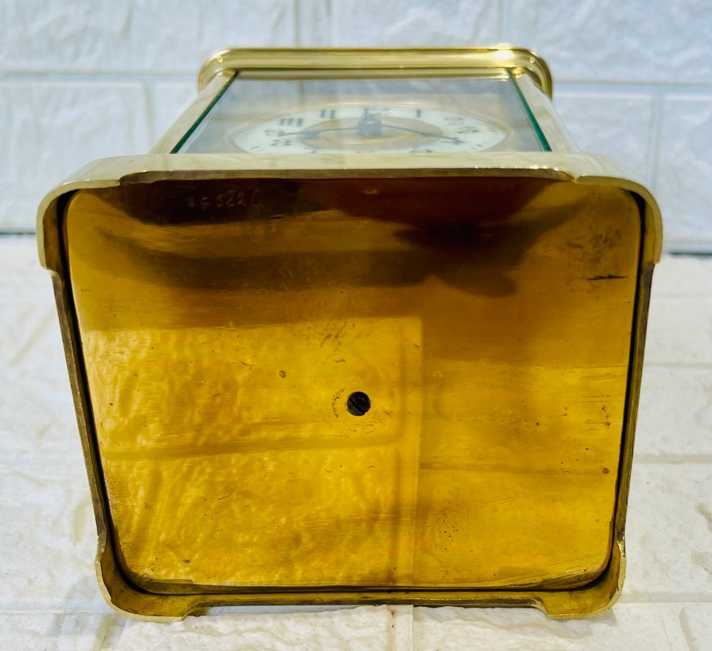 A French brass carriage clock featuring a top carrying handle, clear glass viewing panels, and a white enamel dial with black numerals. View VIII