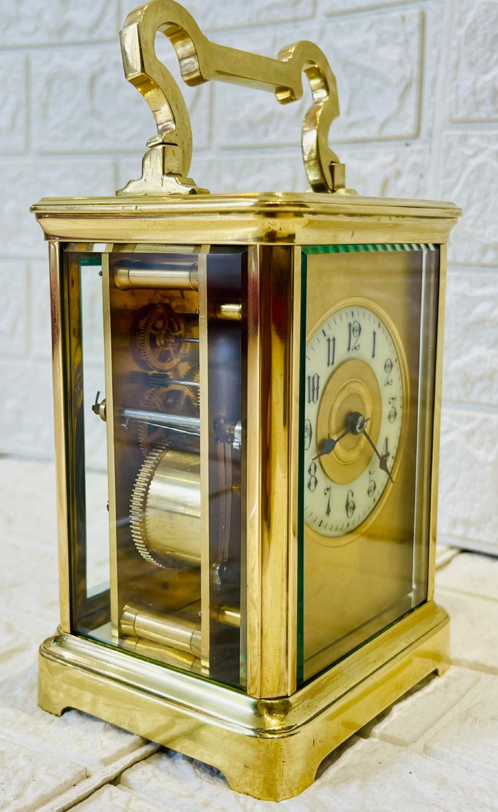 A French brass carriage clock featuring a top carrying handle, clear glass viewing panels, and a white enamel dial with black numerals. View IX