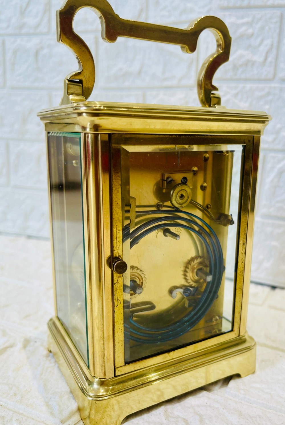 A French brass carriage clock featuring a top carrying handle, clear glass viewing panels, and a white enamel dial with black numerals. View XI