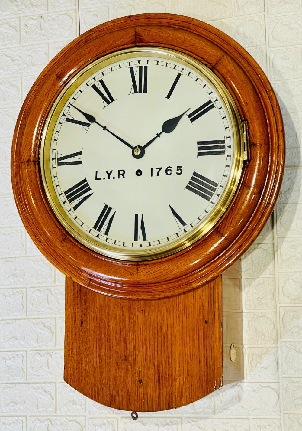 An antique oak drop dial wall clock featuring a white face with Roman numerals, marked L.Y.R 1765 with a brass bezel. View VI