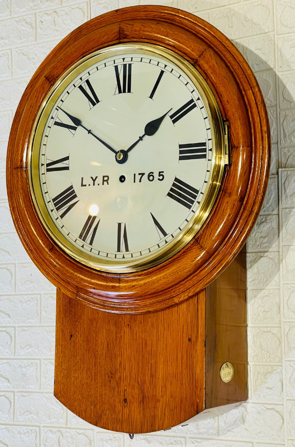An antique oak drop dial wall clock featuring a white face with Roman numerals, marked L.Y.R 1765 with a brass bezel. View VII