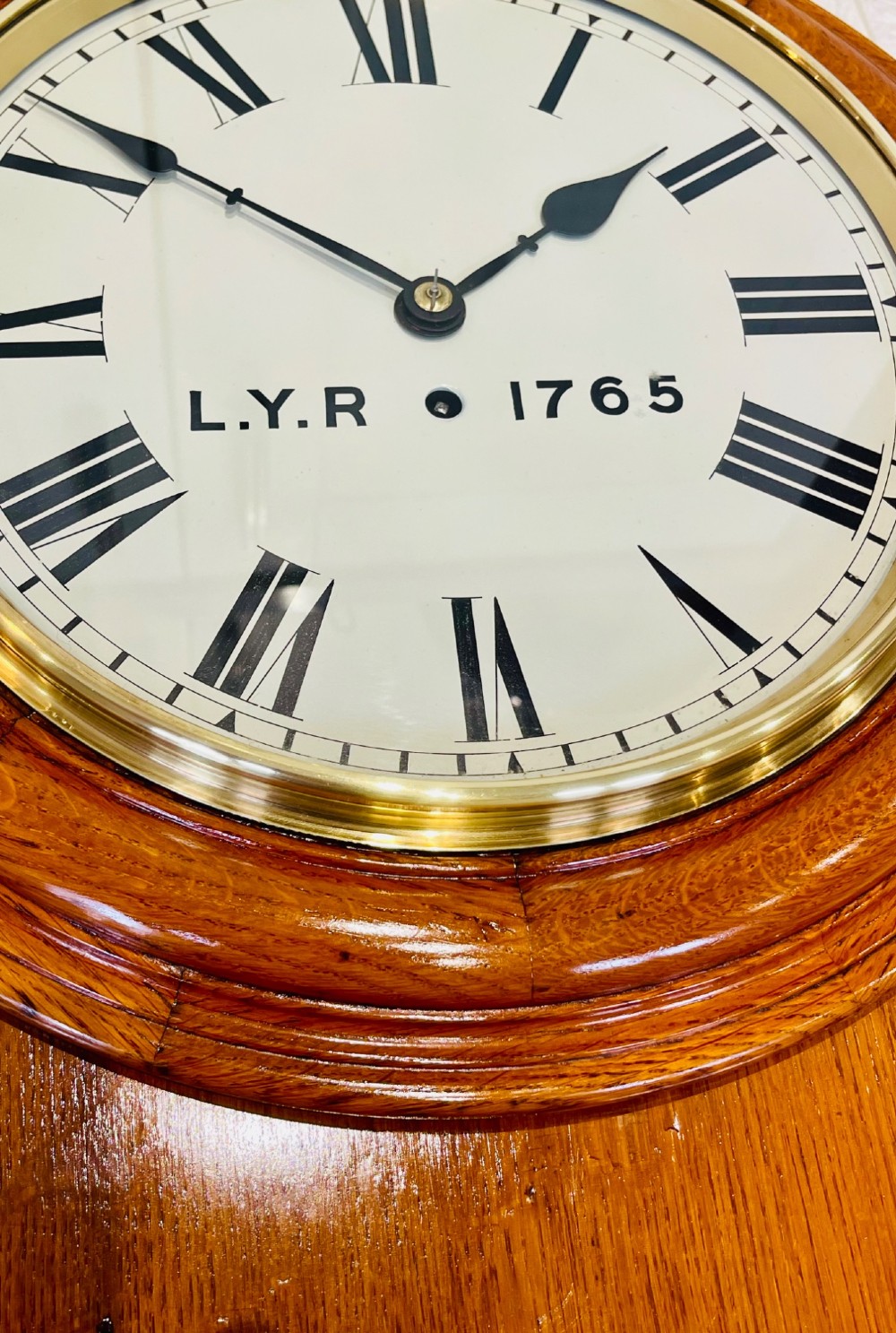An antique oak drop dial wall clock featuring a white face with Roman numerals, marked L.Y.R 1765 with a brass bezel. View IX
