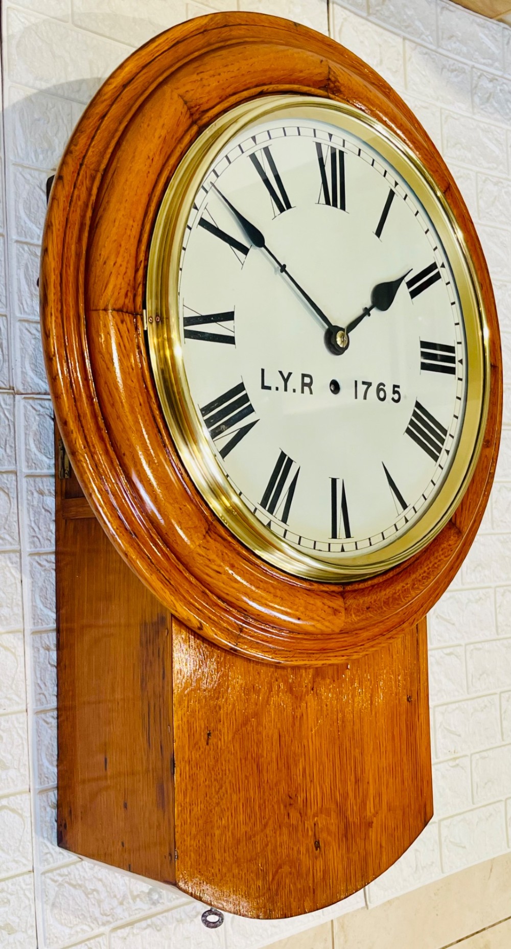 An antique oak drop dial wall clock featuring a white face with Roman numerals, marked L.Y.R 1765 with a brass bezel. View XI