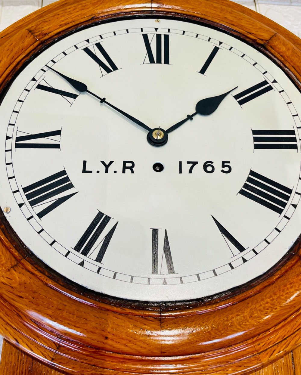 An antique oak drop dial wall clock featuring a white face with Roman numerals, marked L.Y.R 1765 with a brass bezel. View XIV