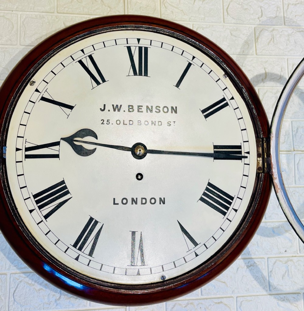 A circular mahogany fusee wall clock featuring a white dial face with black Roman numerals, brass bezel, and J. W. Benson London markings. View X