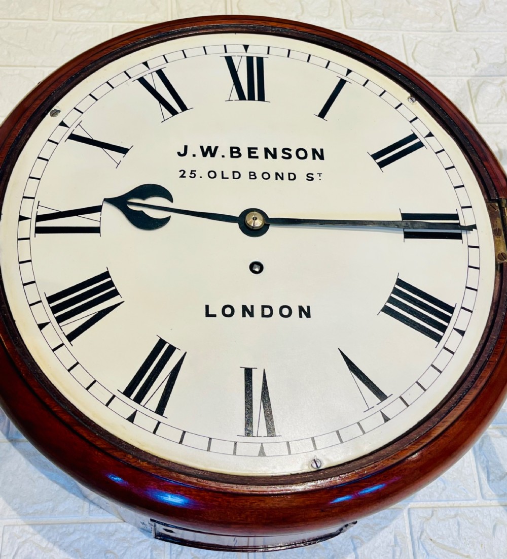 A circular mahogany fusee wall clock featuring a white dial face with black Roman numerals, brass bezel, and J. W. Benson London markings. View XI