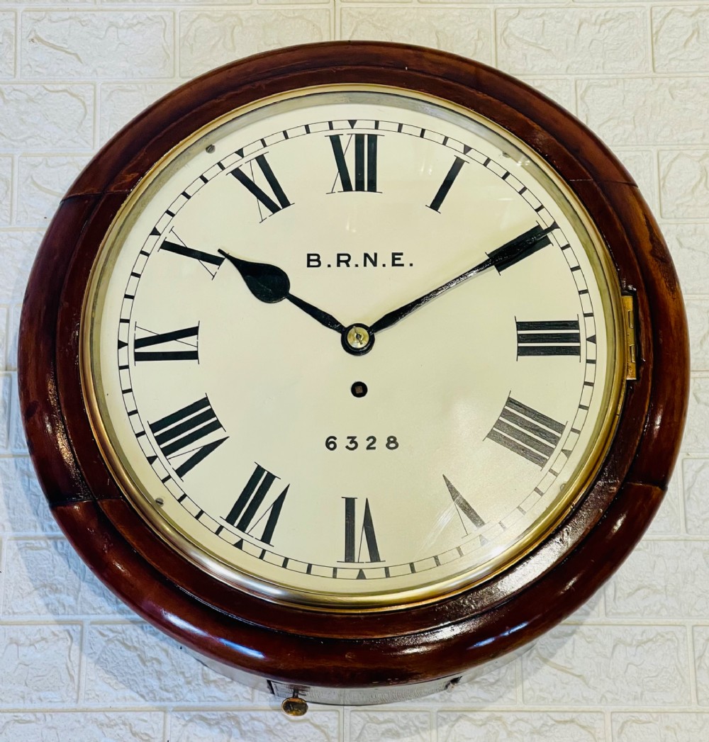 A circular Victorian railway dial clock with a dark mahogany frame, brass bezel, and off-white dial featuring black Roman numerals. View II