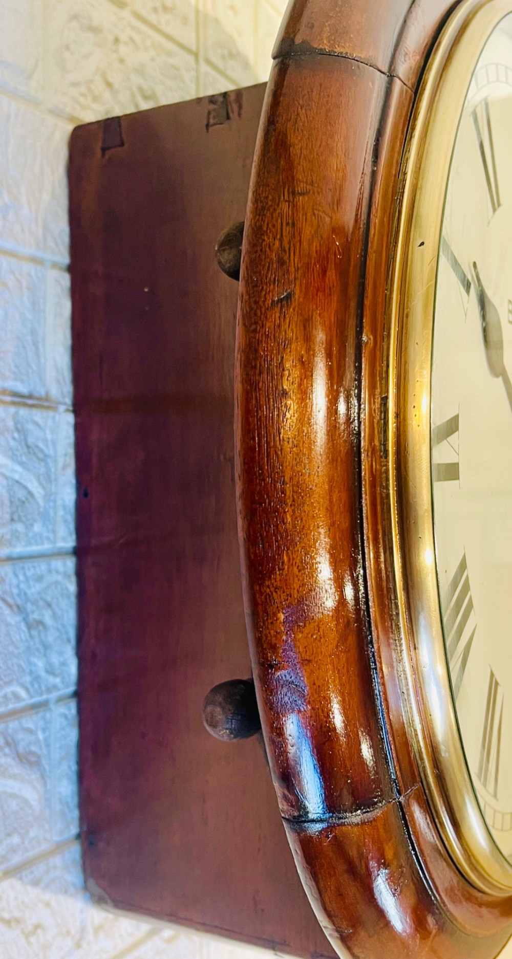 A circular Victorian railway dial clock with a dark mahogany frame, brass bezel, and off-white dial featuring black Roman numerals. View VII