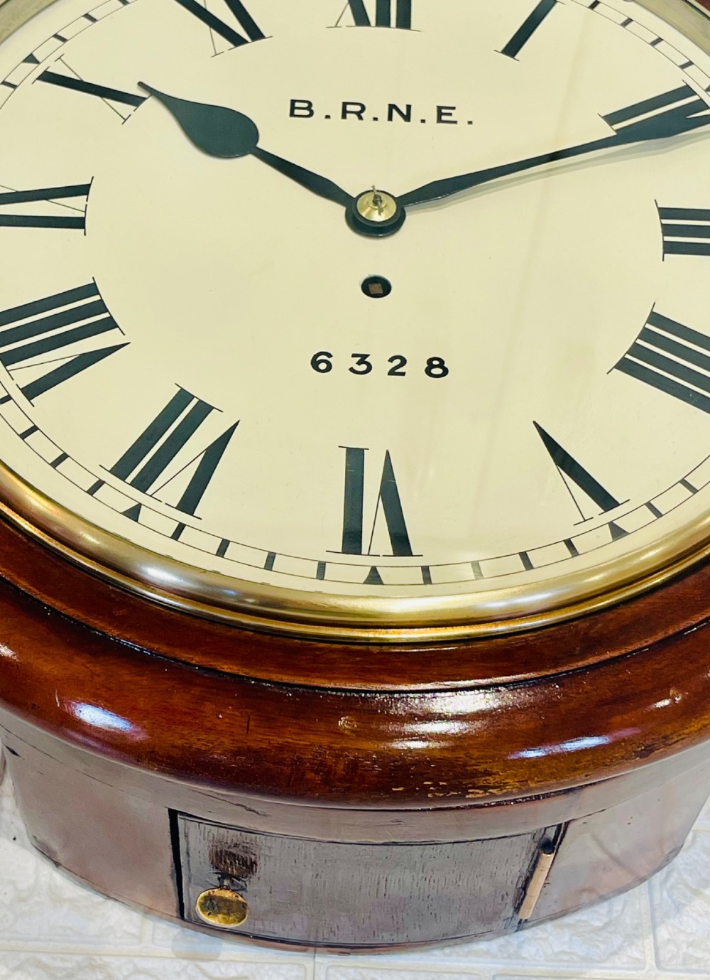 A circular Victorian railway dial clock with a dark mahogany frame, brass bezel, and off-white dial featuring black Roman numerals. View VIII