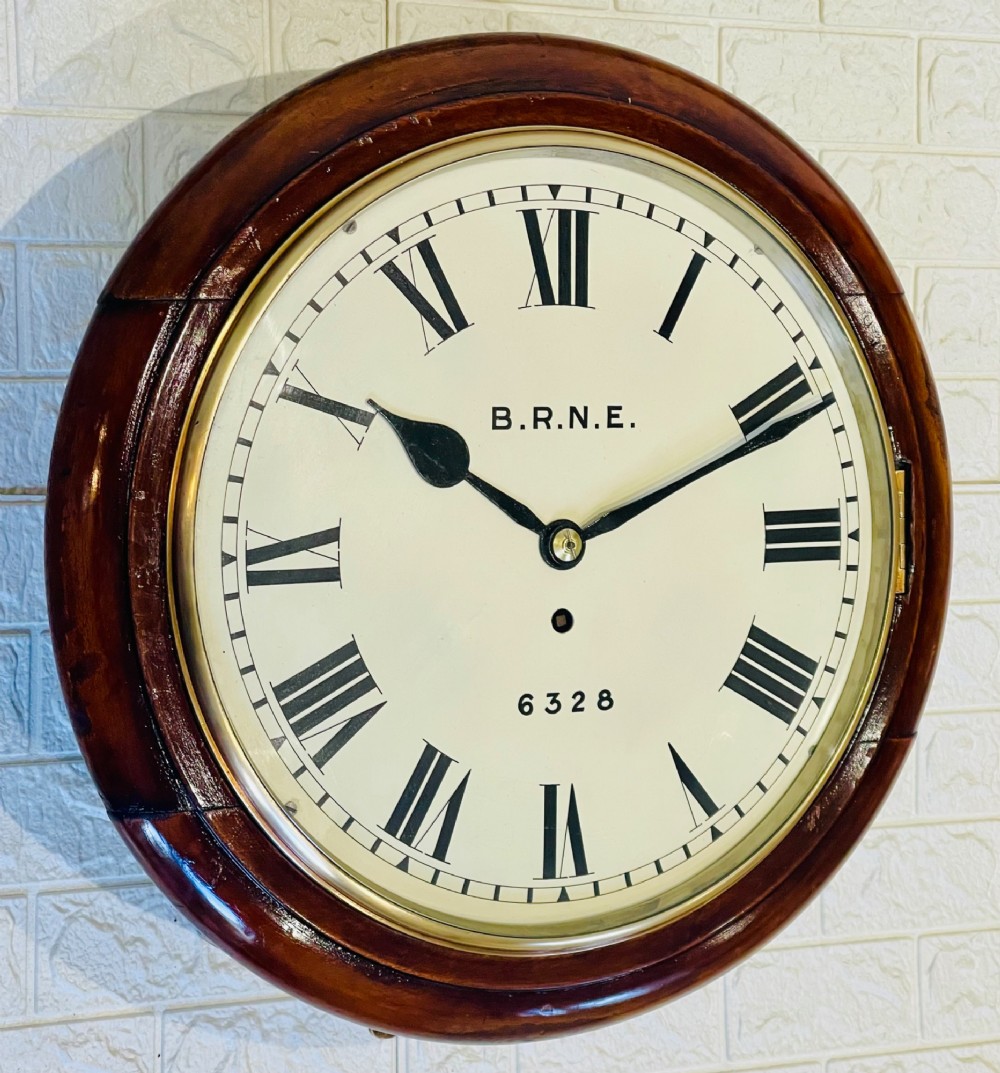 A circular Victorian railway dial clock with a dark mahogany frame, brass bezel, and off-white dial featuring black Roman numerals. View IX