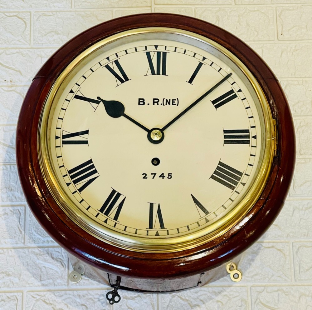 A circular 10-inch railway dial wall clock featuring a turned mahogany wooden surround, a brass bezel, and a cream dial marked B.R.(NE) with black Roman numerals. View III
