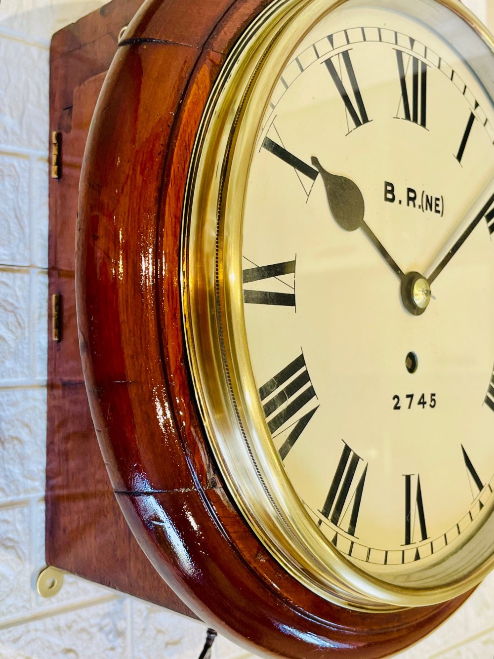 A circular 10-inch railway dial wall clock featuring a turned mahogany wooden surround, a brass bezel, and a cream dial marked B.R.(NE) with black Roman numerals. View VIII