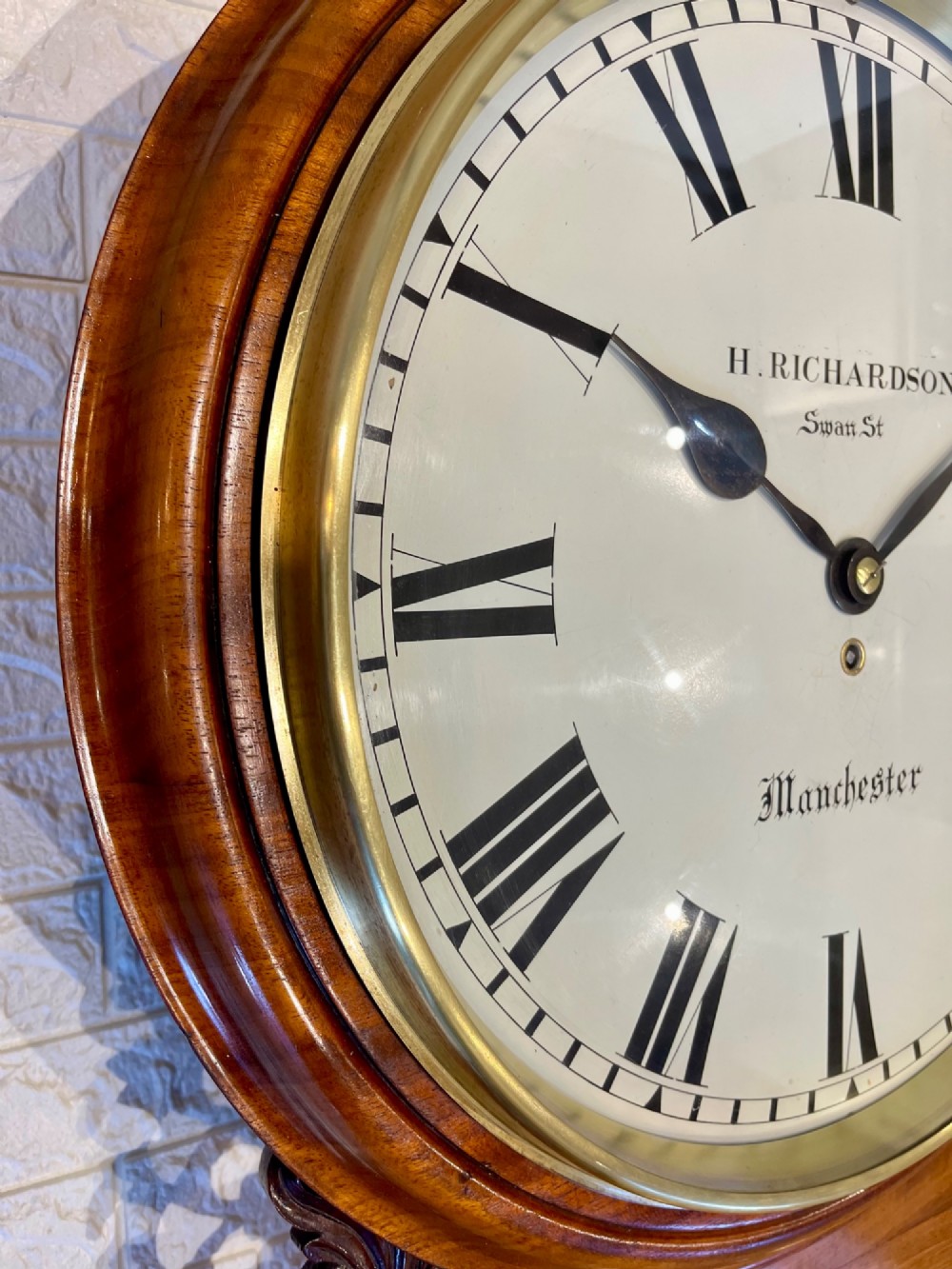 Victorian oak drop dial wall clock featuring a circular white dial with Roman numerals, a brass bezel, and carved side scrolls. View XI