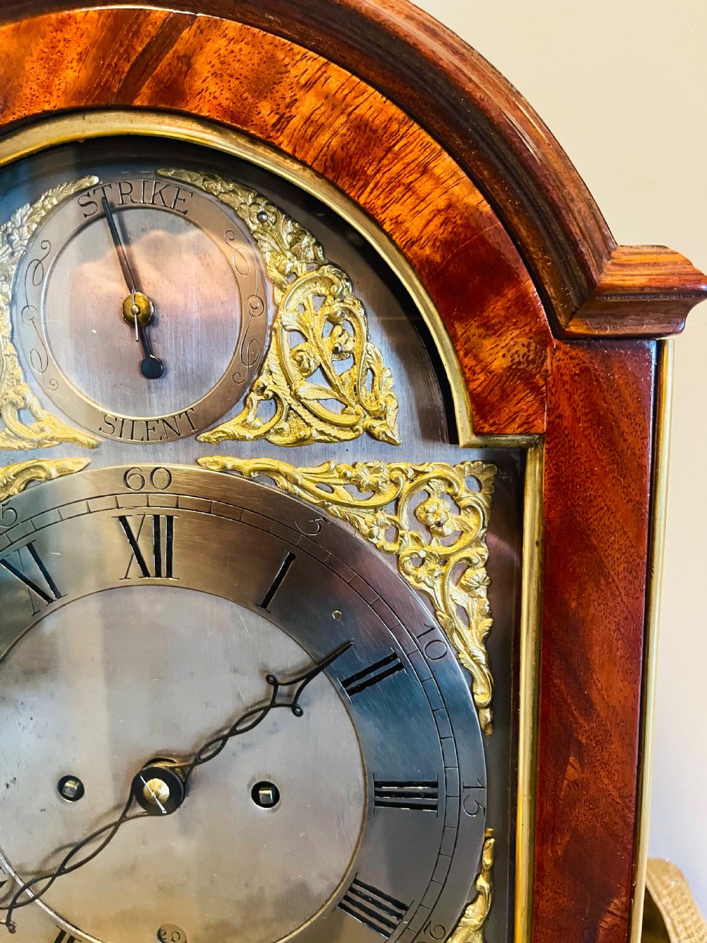 A George III mahogany bracket clock featuring an arched case with a brass top handle, gilt spandrels, and a silvered dial. View II