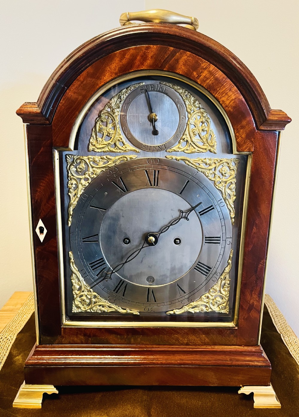 A George III mahogany bracket clock featuring an arched case with a brass top handle, gilt spandrels, and a silvered dial. View V