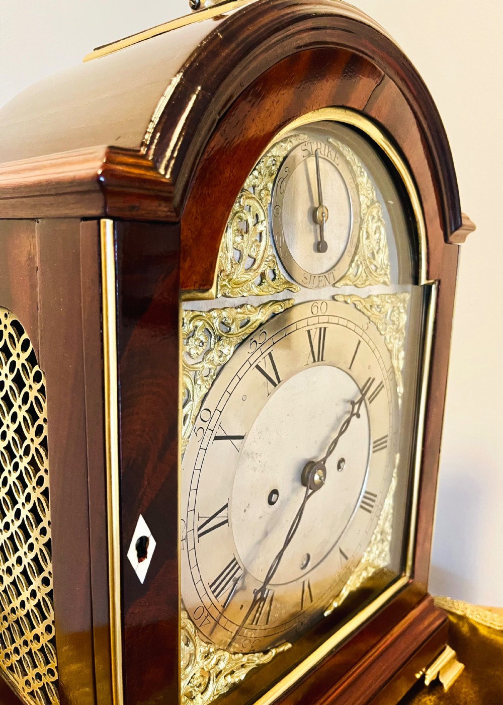 A George III mahogany bracket clock featuring an arched case with a brass top handle, gilt spandrels, and a silvered dial. View VI