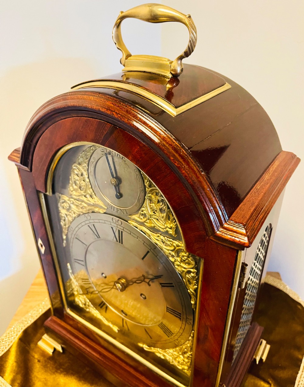A George III mahogany bracket clock featuring an arched case with a brass top handle, gilt spandrels, and a silvered dial. View XIV