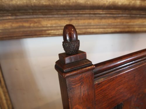 fig 1. An eighteenth-century dark oak wainscot armchair featuring a panelled backrest, carved finials, turned front legs, and sturdy wooden stretchers.