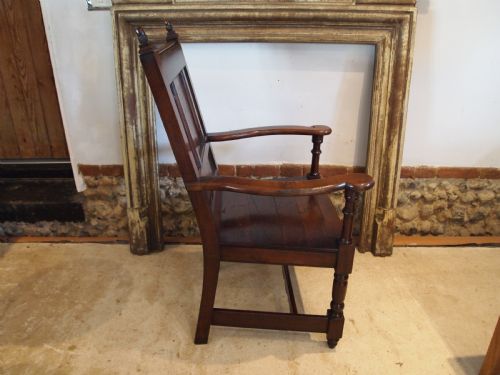 fig 3. An eighteenth-century dark oak wainscot armchair featuring a panelled backrest, carved finials, turned front legs, and sturdy wooden stretchers.