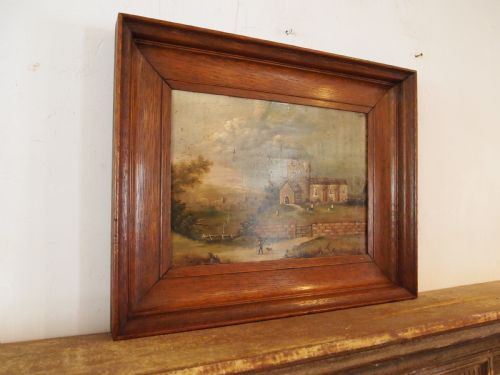 fig 2. A 19th-century naive oil painting on board depicting a rural church scene with a figure walking a dog, set within a wide wooden frame.