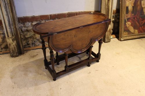 fig 3. A late Victorian walnut occasional table featuring a scalloped multi-lobed top with a raised rim, supported by turned legs and cross stretchers.