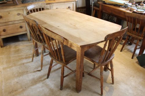fig 1. An Edwardian light oak dining table featuring a rectangular top with subtly curved short ends, supported by four straight square legs.