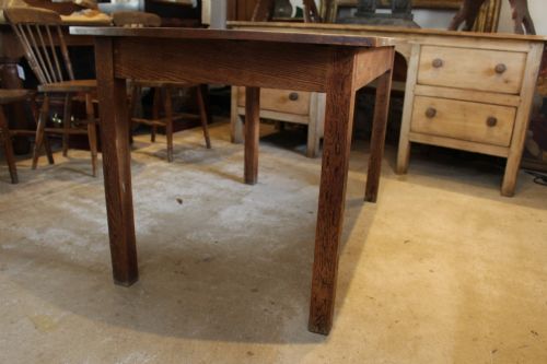 fig 5. An Edwardian light oak dining table featuring a rectangular top with subtly curved short ends, supported by four straight square legs.