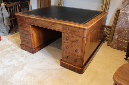 fig 2. An early Victorian mahogany partners desk featuring a black leather writing top, twin pedestals with multiple drawers, and turned wooden handles.