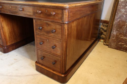 fig 4. An early Victorian mahogany partners desk featuring a black leather writing top, twin pedestals with multiple drawers, and turned wooden handles.