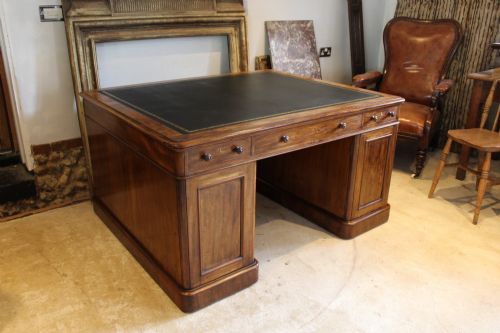 fig 5. An early Victorian mahogany partners desk featuring a black leather writing top, twin pedestals with multiple drawers, and turned wooden handles.