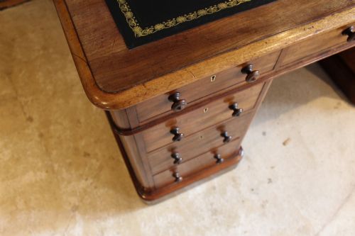 fig 10. An early Victorian mahogany partners desk featuring a black leather writing top, twin pedestals with multiple drawers, and turned wooden handles.