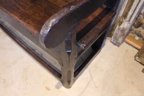 fig 1. A dark oak 17th-century style settle bench with a three-panel backrest, shaped armrests, and wooden stretchers.