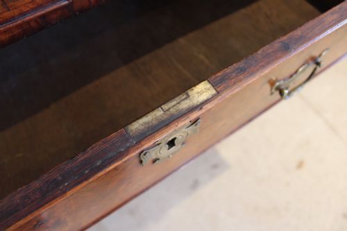 fig 7. A compact George II walnut chest of drawers featuring decorative brass handles, crossbanded veneer top, and turned bun feet.
