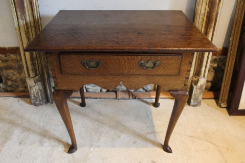 fig 1. A George II oak lowboy table featuring a single drawer with brass handles, a scalloped apron, and slender cabriole legs ending in pad feet.