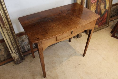 fig 5. A George III country oak side table featuring a single frieze drawer with a brass drop handle, a shaped apron, and four straight legs.