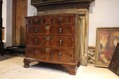 fig 1. An 18th-century George II burr walnut chest of drawers featuring two short over three long graduated drawers on bracket feet.