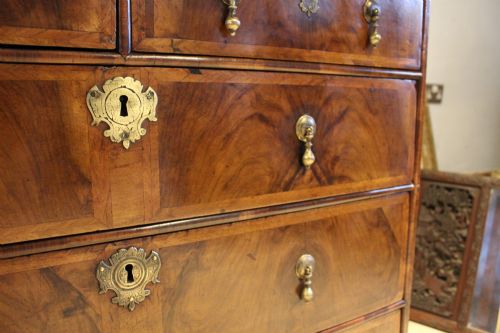 fig 2. An 18th-century George II burr walnut chest of drawers featuring two short over three long graduated drawers on bracket feet.