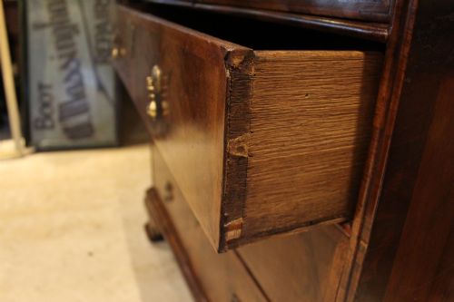 fig 3. An 18th-century George II burr walnut chest of drawers featuring two short over three long graduated drawers on bracket feet.